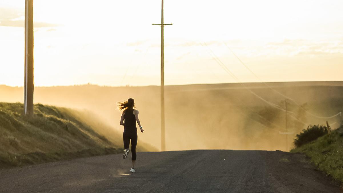 一个女人在一条土路上奔跑的照片.